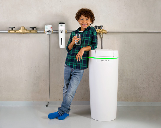 Wasseraufbereitung-Sandholzer gluecklicher junge vor wasseraufbereitungsanlage mit glas wasser in der hand